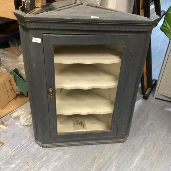Vintage painted corner cabinet with interior shelving for display.