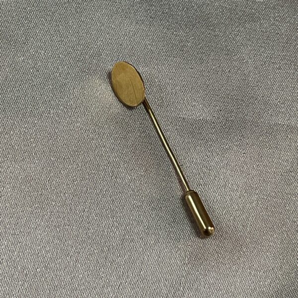 Vintage 9ct gold tie pin on textured fabric.