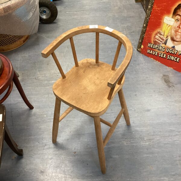 Vintage wooden child’s high chair with slat seat and curved back.