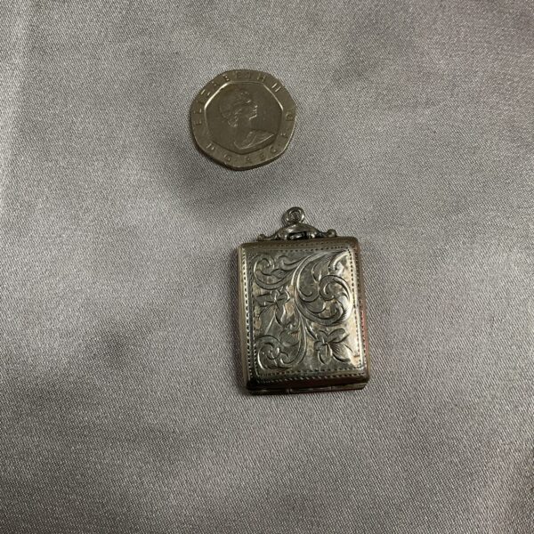 Antique silver fob case with a coin for scale.