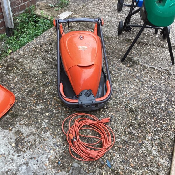 Flymo compact electric mower in a garden setting.