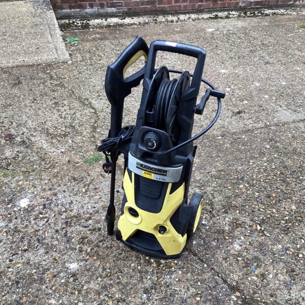 Yellow Karcher pressure washer with hose reel for garden cleaning.