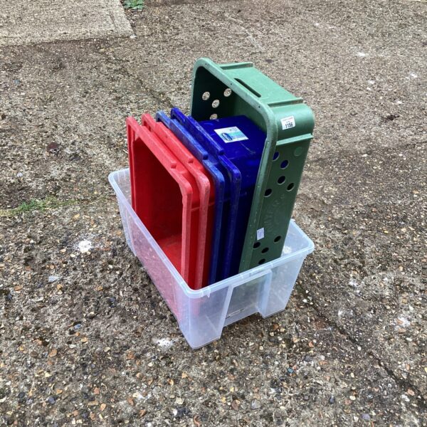Stack of red, blue, and green plastic storage boxes for household organisation.