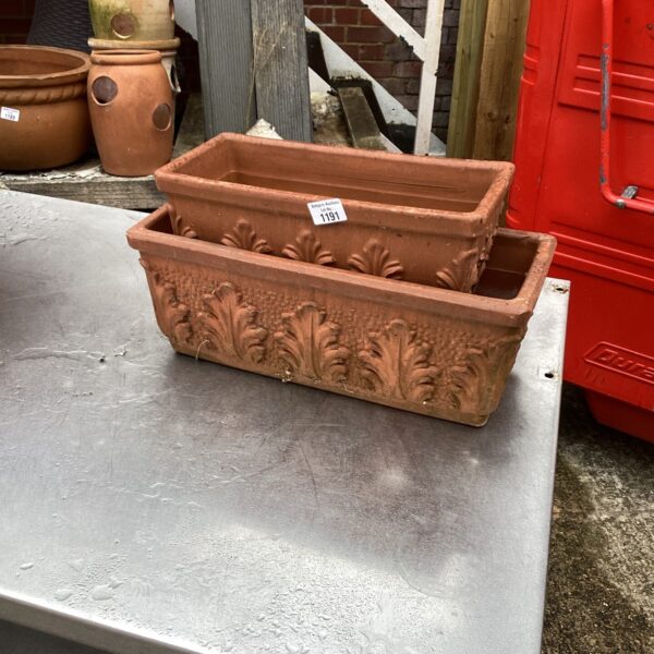 Two weathered terracotta garden planters with embossed detailing for outdoor plants.