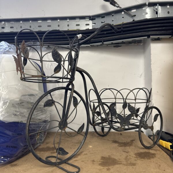 Vintage wrought iron tricycle plant stand for garden display.