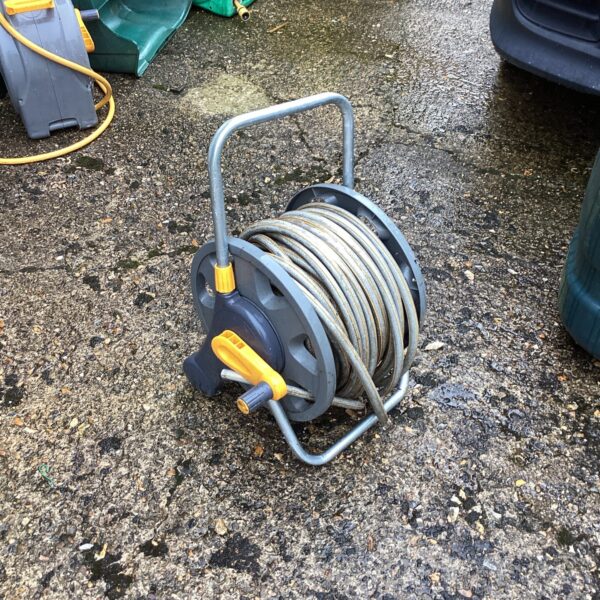 Used garden hose reel with a metal frame and wound hose.