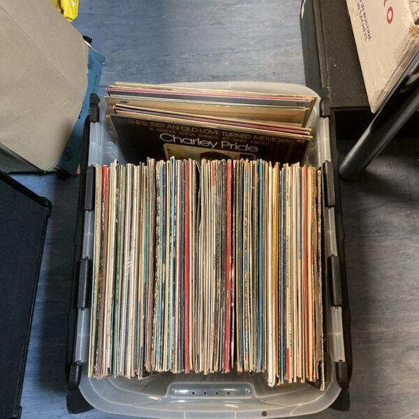 Mixed vinyl record collection in a storage container.