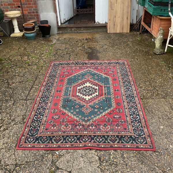 Vintage floral rug with red and blue pattern on a garden patio.