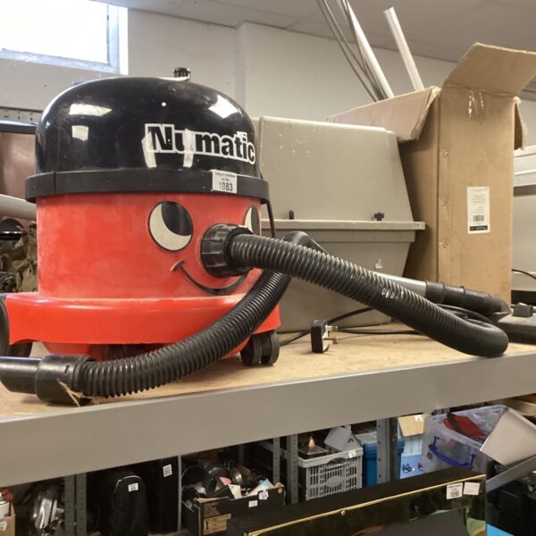 Red Numatic Henry hoover with flexible hose for cleaning.