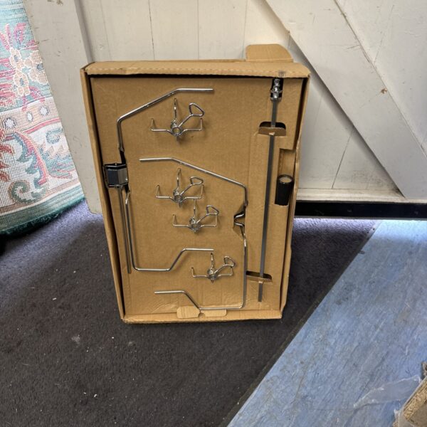 Close-up of barbecue rotisserie kit with metal forks and rods.