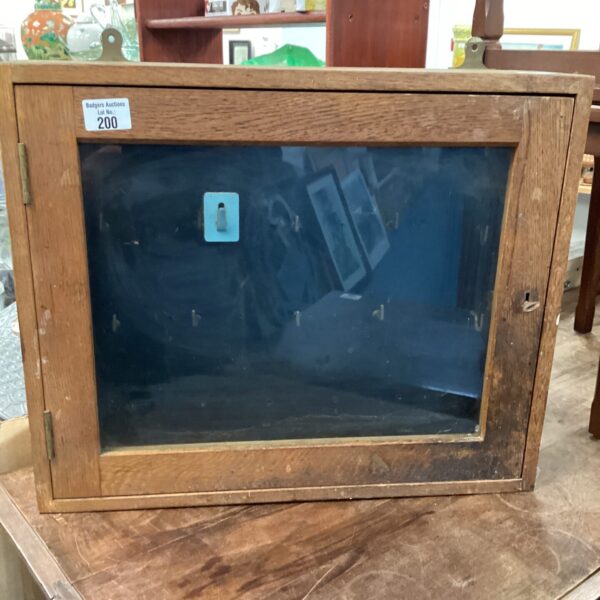 Vintage wooden key cabinet with glass front for secure storage.