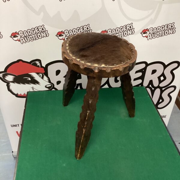 Vintage cowhide stool with three wooden legs, rustic farmhouse style.