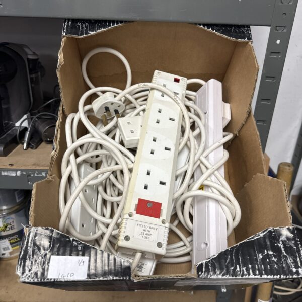 Assorted extension leads in a cardboard box, power strip lot.