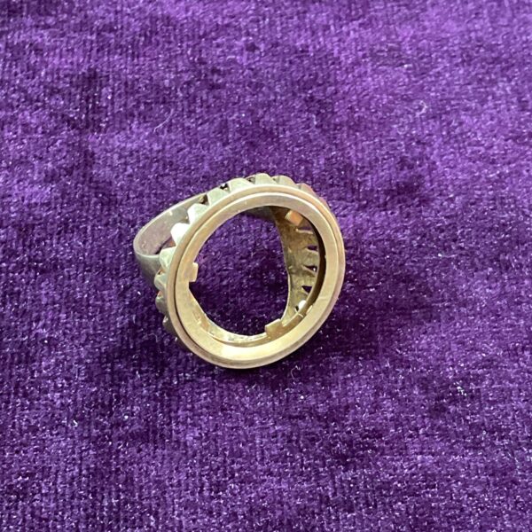 Close-up of 9ct gold sovereign ring holder on purple fabric.