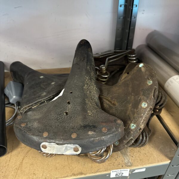 Worn vintage bicycle saddle with leather seat and springs.