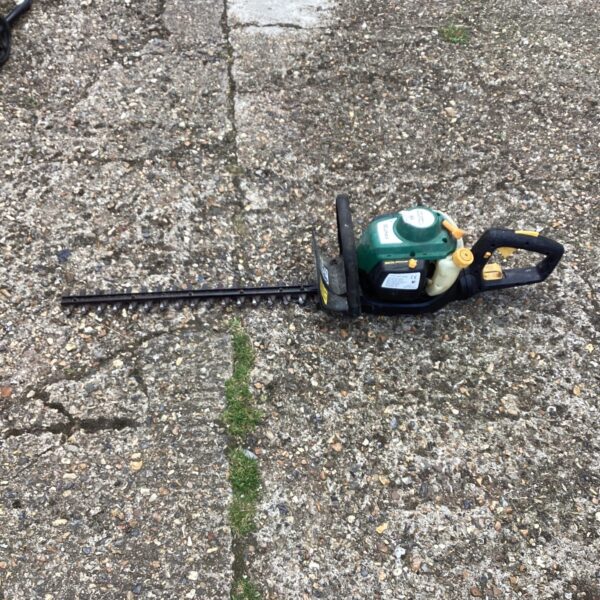 Used petrol hedge trimmer with long blade for garden landscaping.
