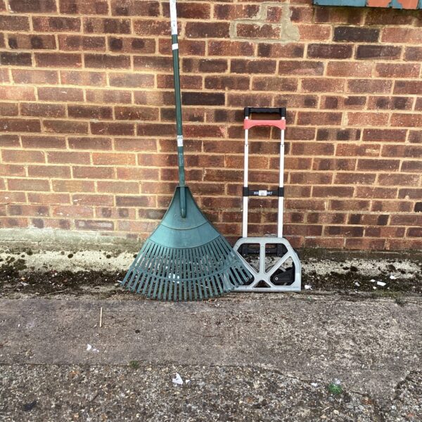 Folding garden trolley and lawn rake set for outdoor use.