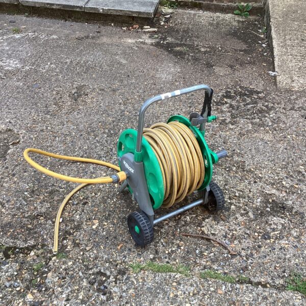 Used Hozelock hose reel with garden hose in outdoor setting.