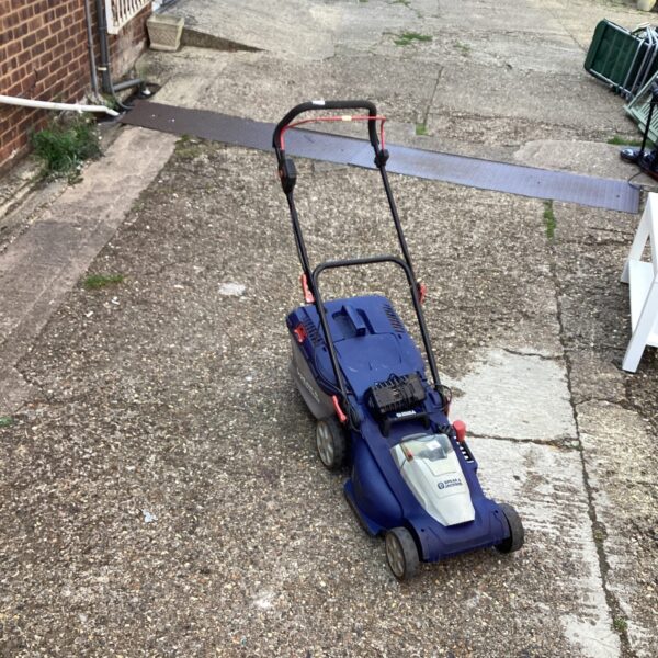 Used Spear and Jackson cordless lawn mower in a garden setting.
