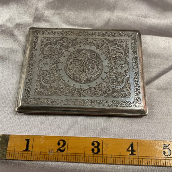Intricate silver plate cigarette case with engraved floral design.