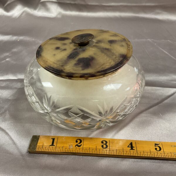 Vintage powder puff pot with faux tortoise shell lid on white background.
