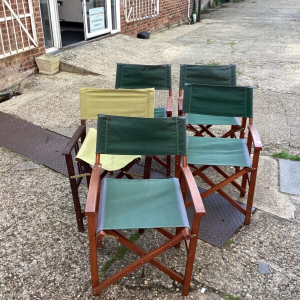 Five vintage folding canvas chairs in a garden setting.