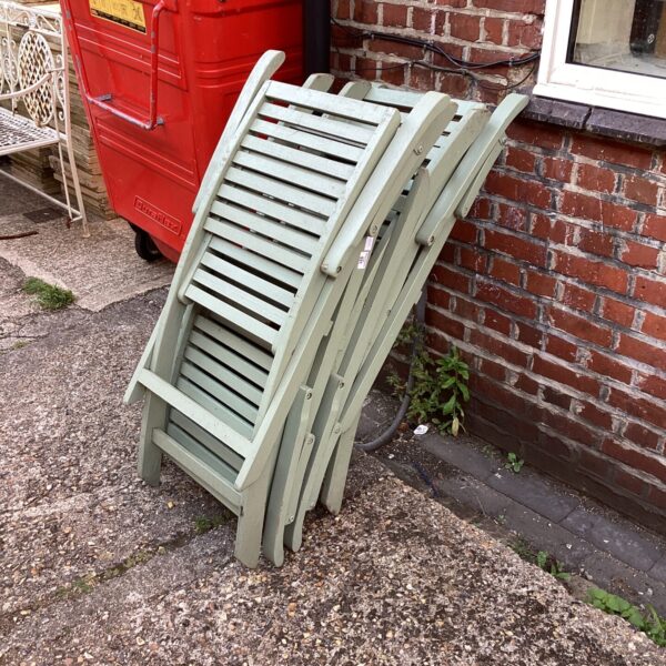 Four vintage wooden folding chairs in a garden setting.