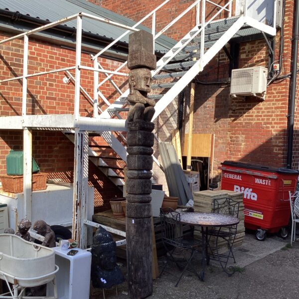 Large weathered wooden totem pole in a garden setting.