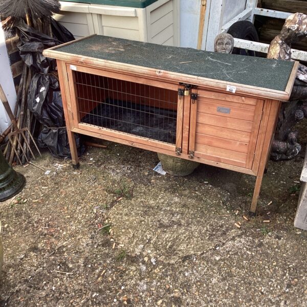 Weathered wooden small animal hutch in a garden setting.