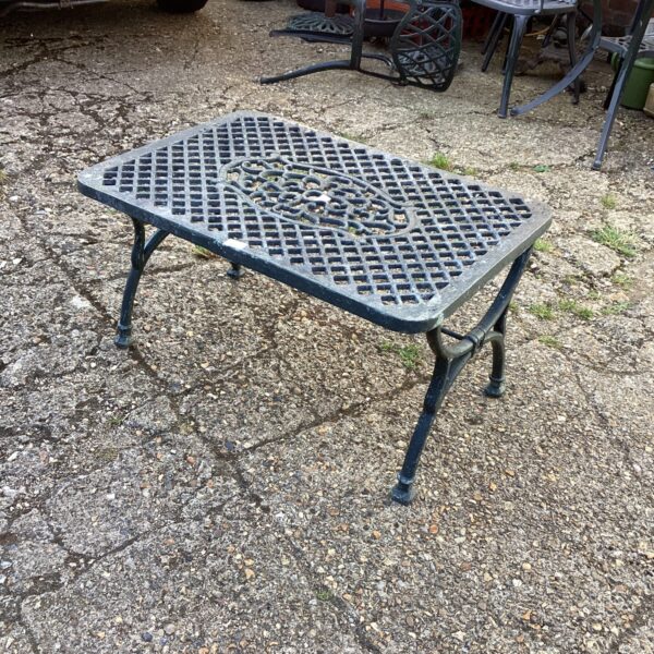 Vintage metal garden table with pierced tabletop in outdoor setting.