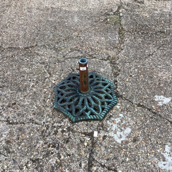 Vintage wrought iron parasol base with star design in garden.