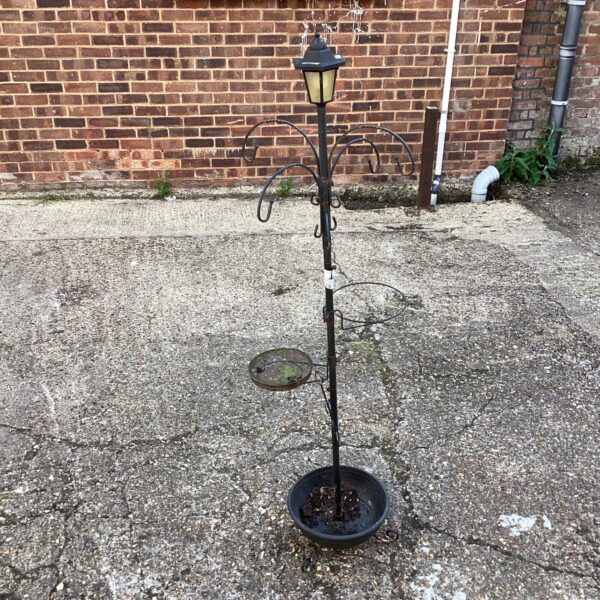 Decorative metal garden bird feeder attracting wildlife.