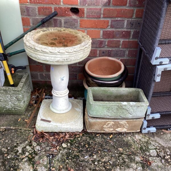 Stone effect garden bird bath with assorted planters in a garden setting.