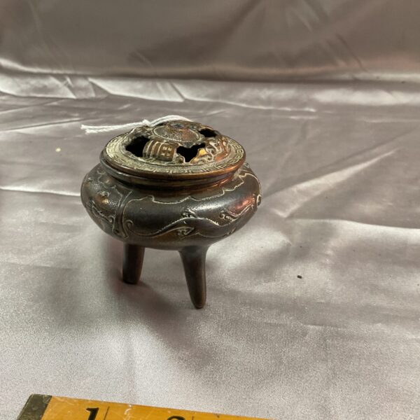 Intricate vintage brass censor with tripod base.