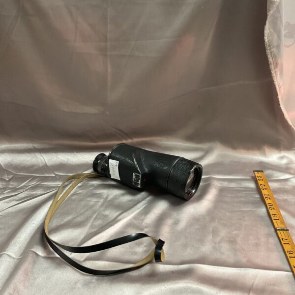 Side view of a vintage military monocular with markings.
