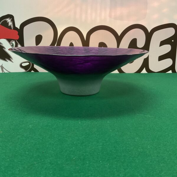 Large purple glass bowl on green surface, decorative centerpiece.