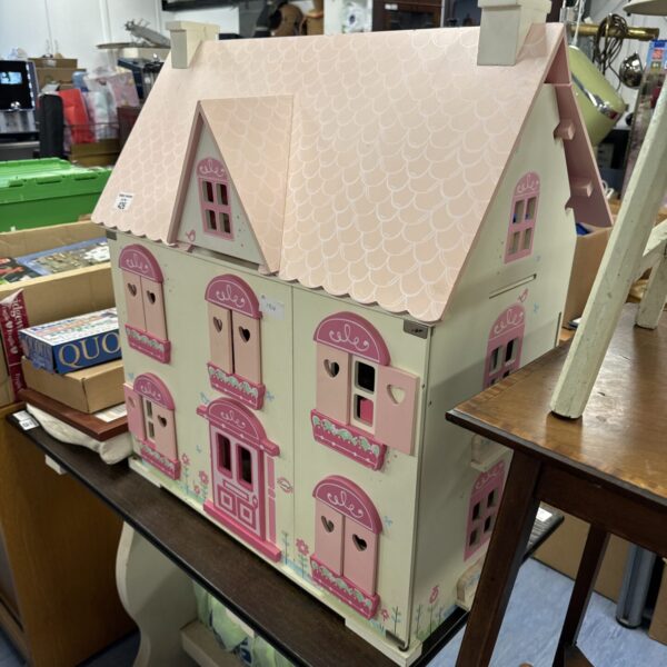 Pink and cream Early Learning Centre dolls house on a table.