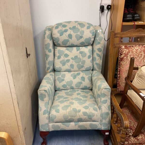 Vintage upholstered armchair with a leaf pattern fabric.