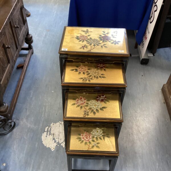 Antique Oriental lacquered tables with floral designs, nested together.