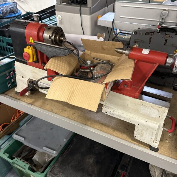 Axminster hobby lathe with attachments on a workshop shelf.
