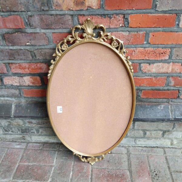 Ornate vintage brass oval mirror for wall decoration.