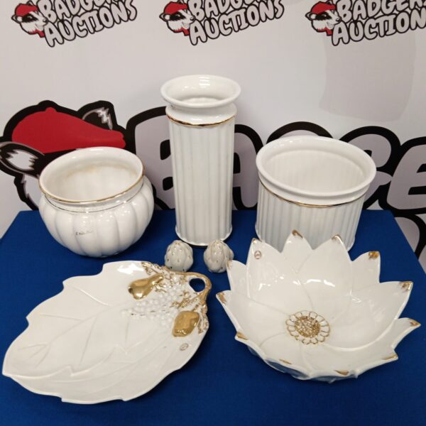 Vintage porcelain pots and bowls with gold trim on display.