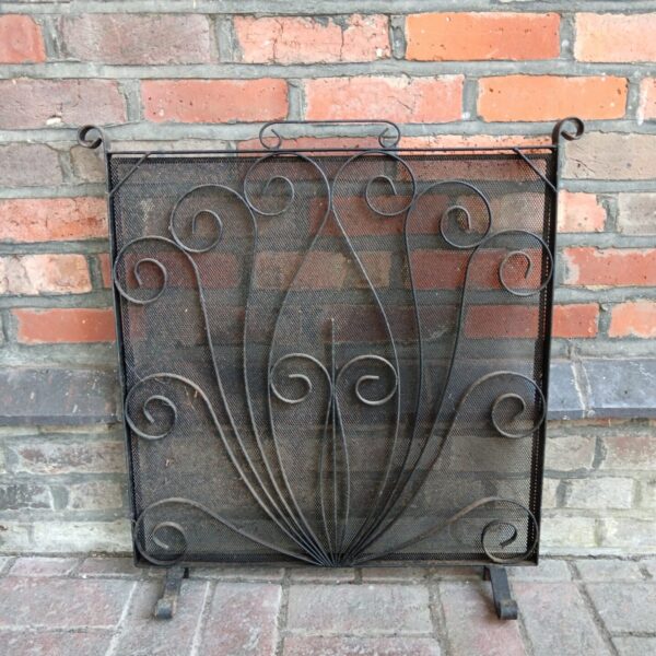 Intricate vintage wrought iron firescreen with fan design.