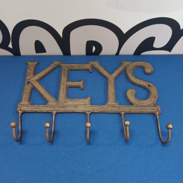 Vintage cast iron key holder with ornate design and hooks.