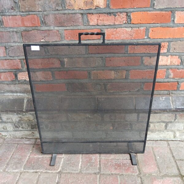 Vintage wrought iron fire guard for fireplace protection.