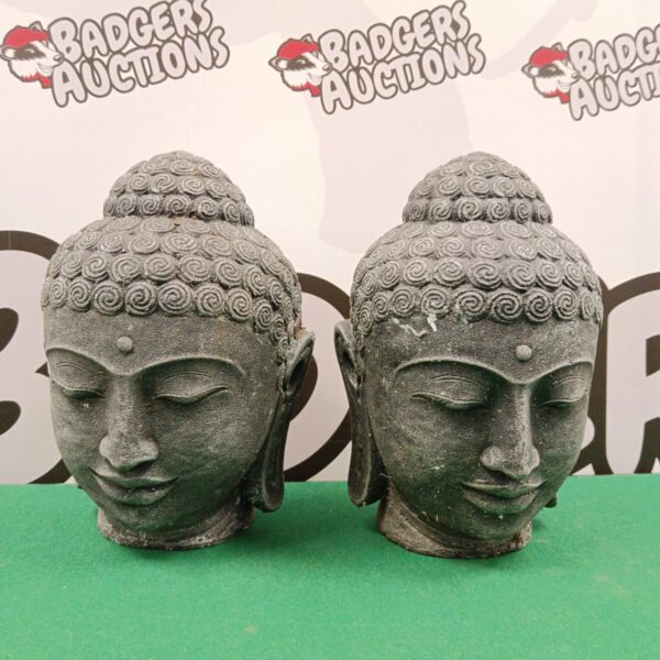 Pair of weathered cast stone Buddha heads for garden or home decor.