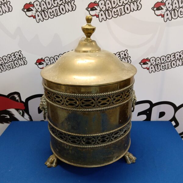 Ornate vintage brass log bin with lion head handles.