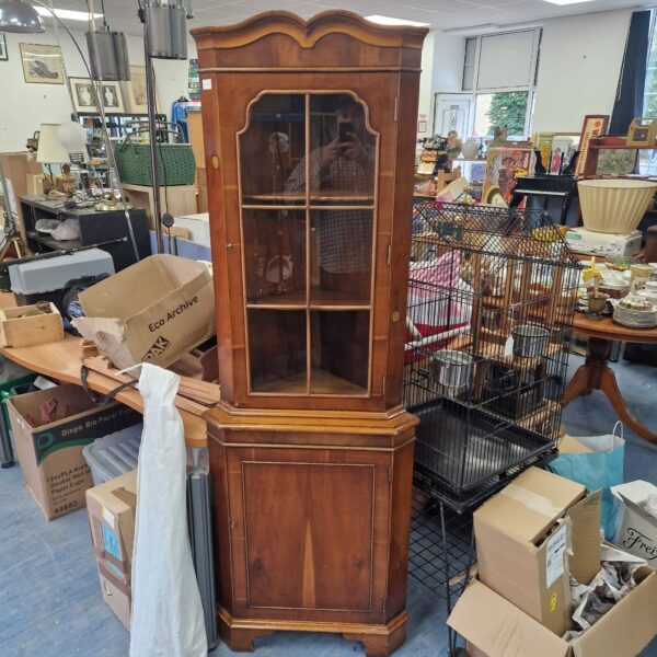 Antique walnut corner cabinet with glazed panels for display.