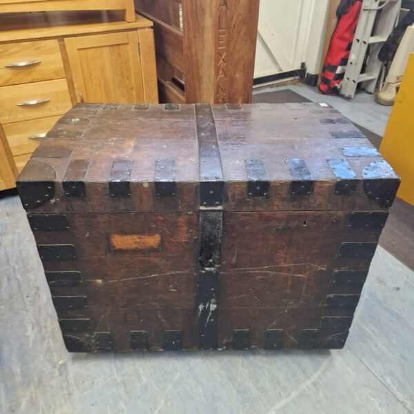 Front view of a large antique iron-banded wooden trunk.