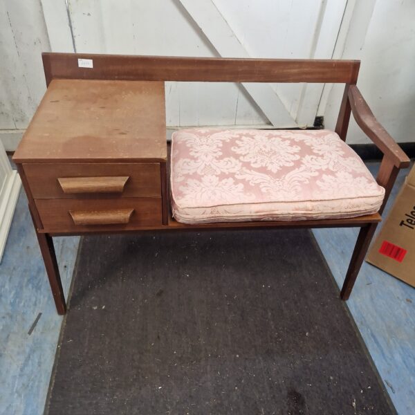 Vintage telephone table with patterned seat in a hallway setting.